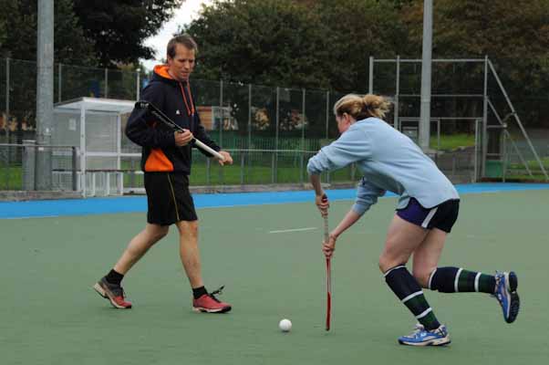 A coach working one to one with a player on an outdoor pitch