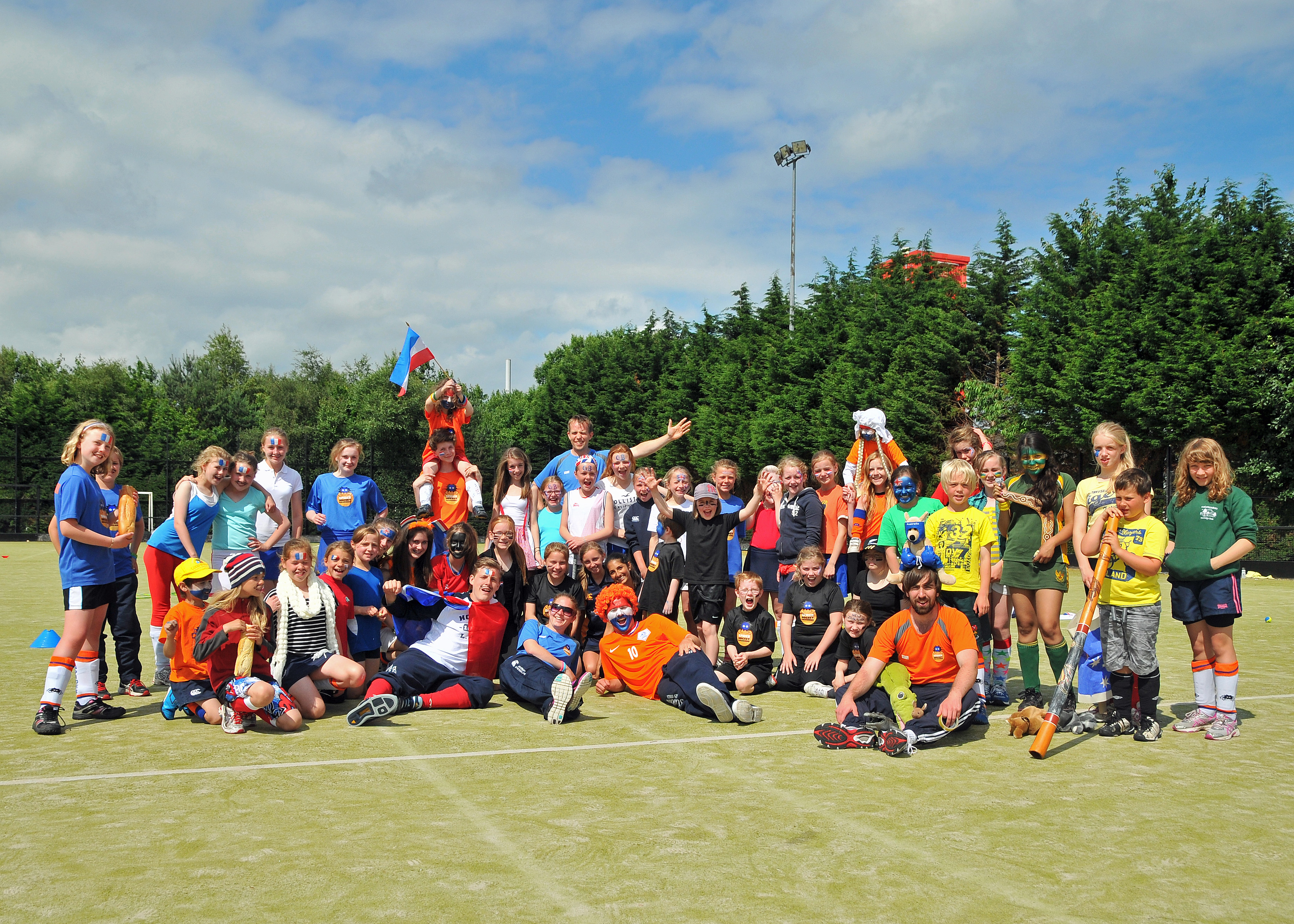 A large group photo of Spider Hockey camp participants and coaches on the pitch