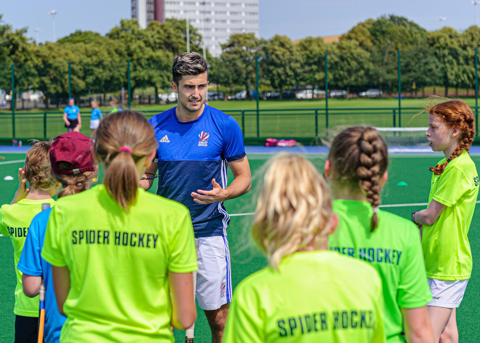 A coach in Scotland kit talking to a group of players in Spider Hockey training tops