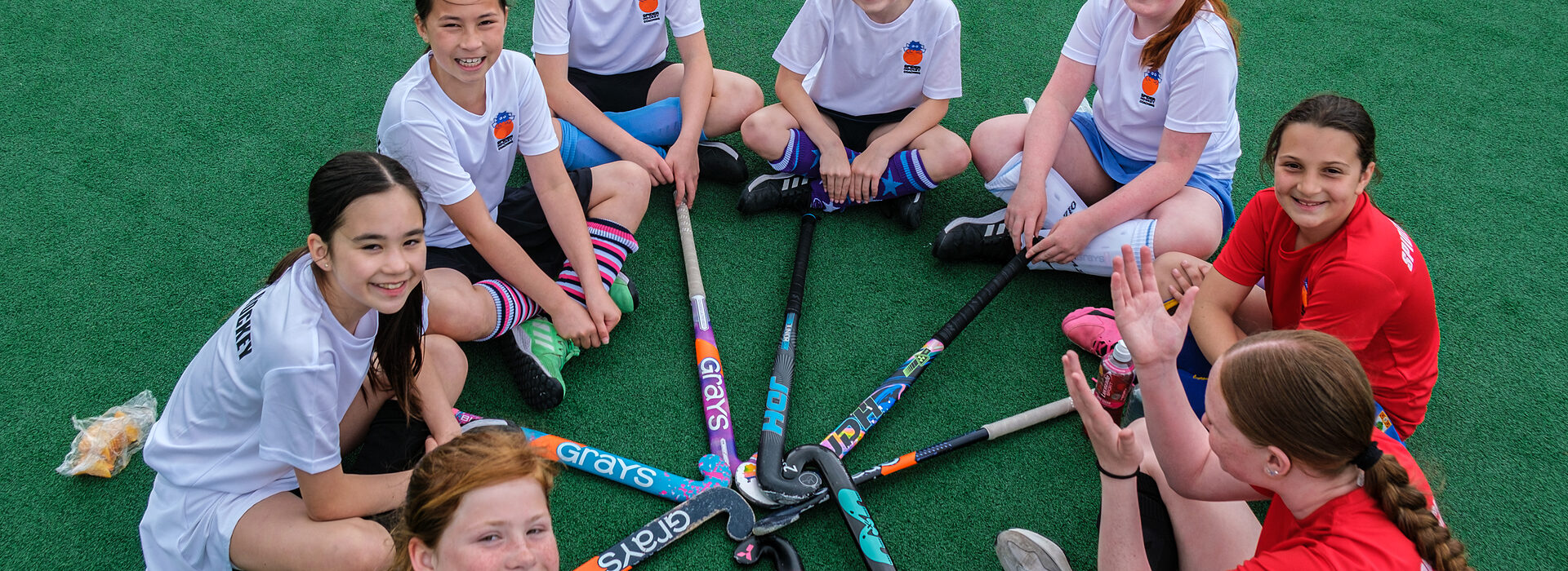 Overhead view of hockey players standing in a circle with their sticks together