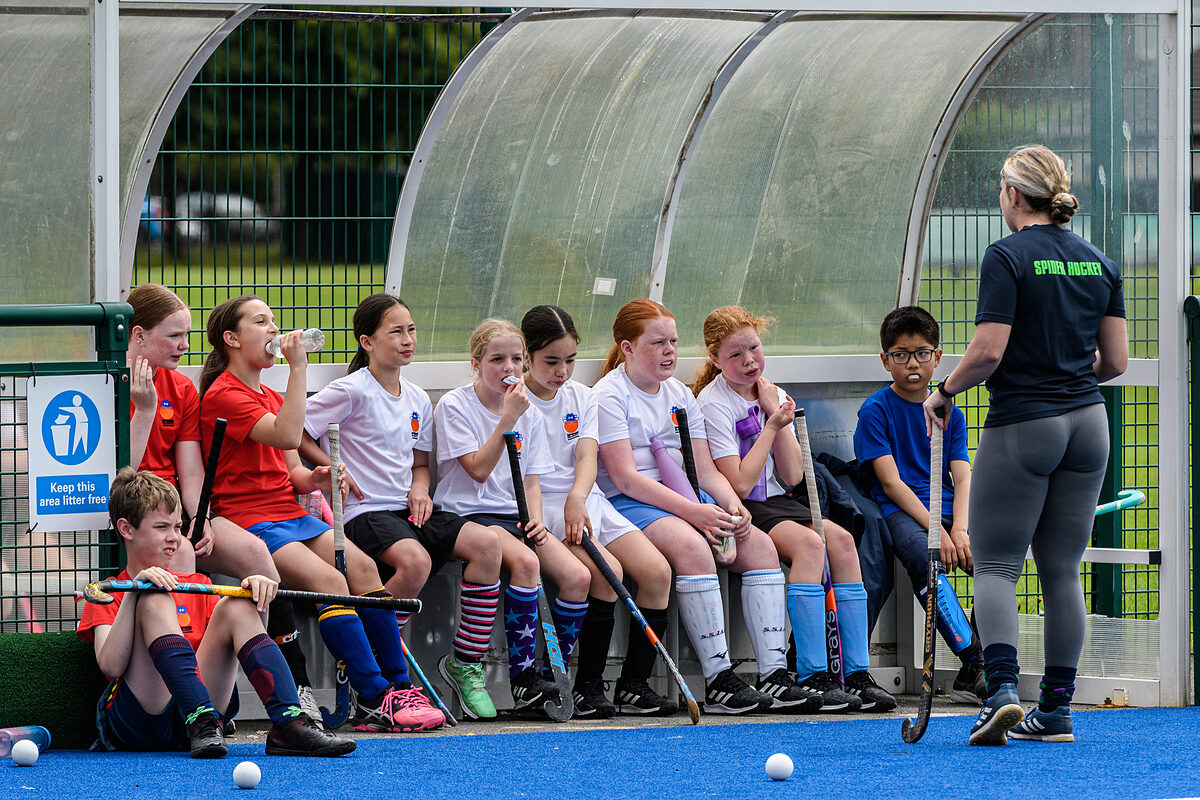 Players sitting on the bench with a coach during a Spider Hockey holiday camp