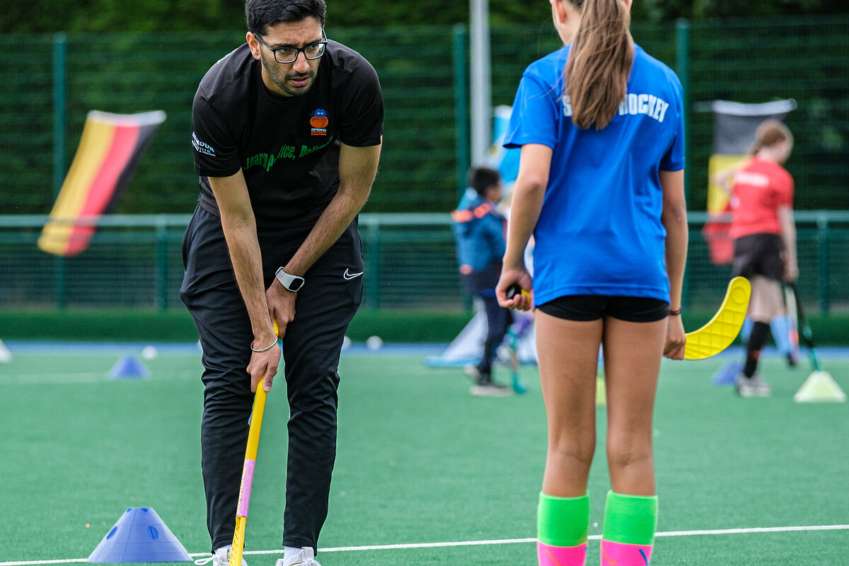 A Spider Hockey coach demonstrating a skill to a group of players