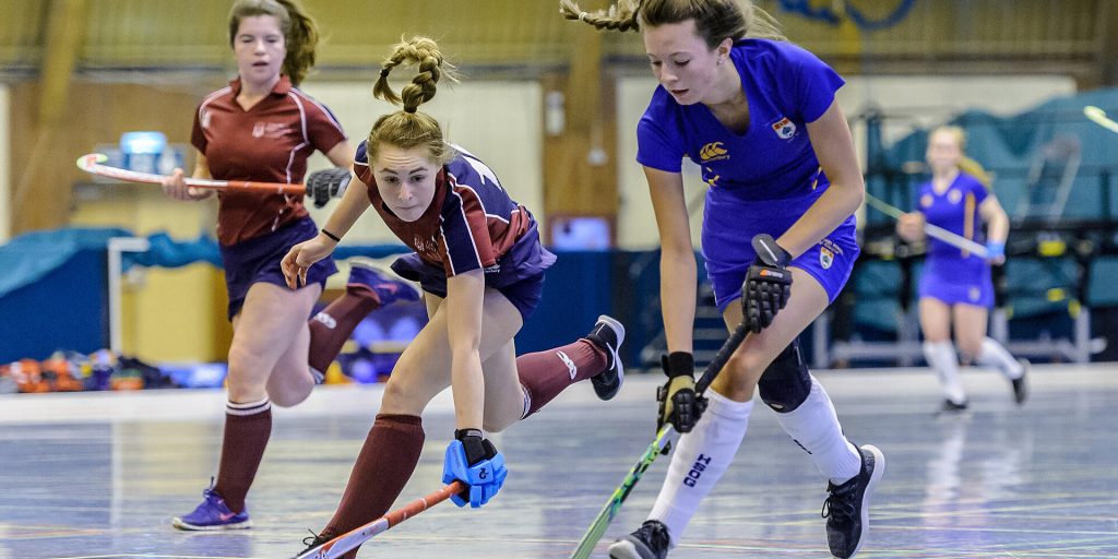Players competing for the ball during an indoor hockey match